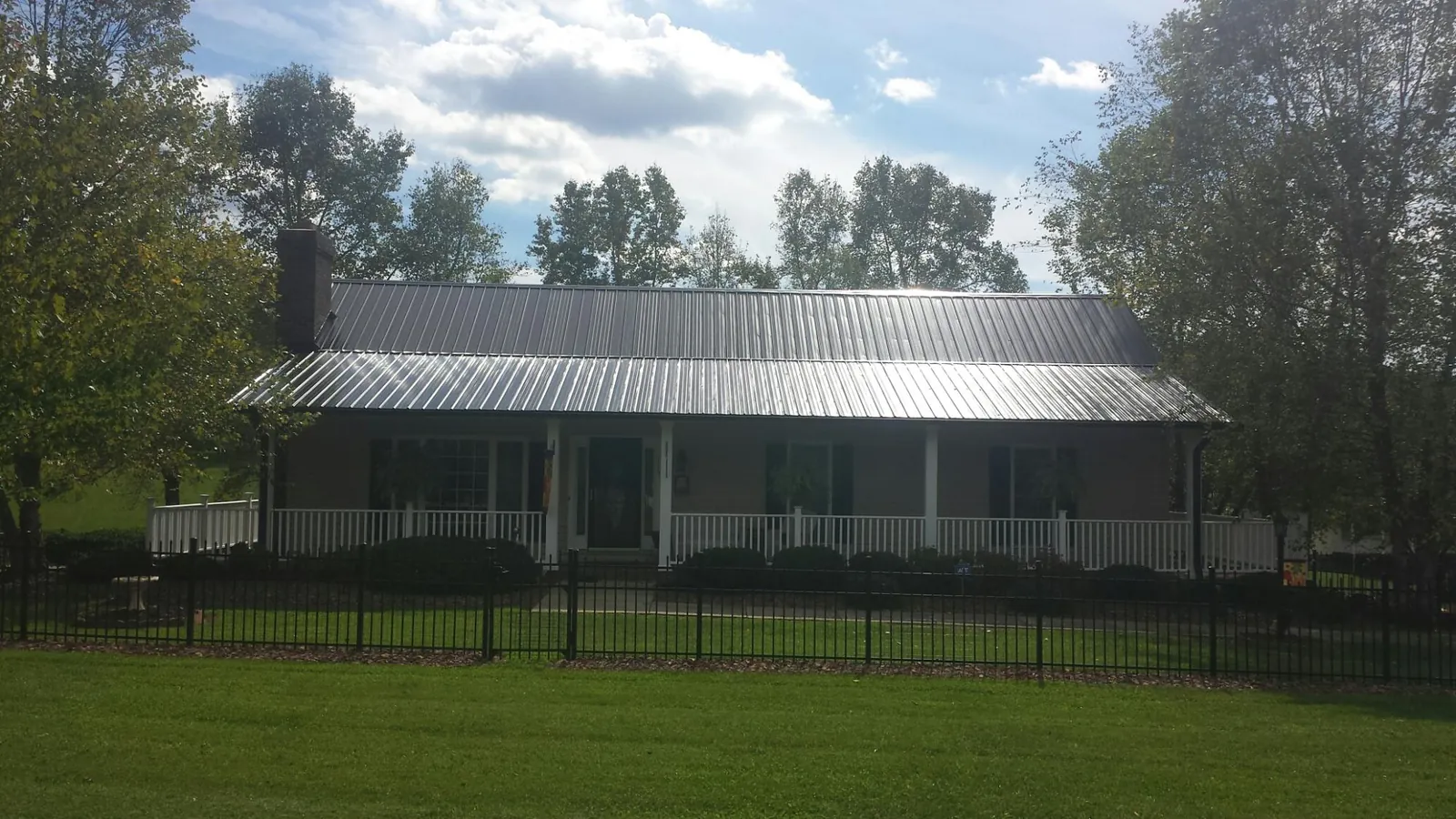 Gray metal roof on a brick ranch with a full width front porch — Gutter Guard Installation work by our crew in Melbourne
