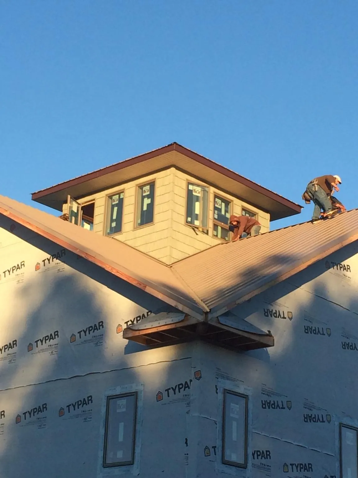 Roofers working around a rooftop cupola on a new metal roof at sunset — Roof Waterproofing in Melbourne by Roofing Brothers